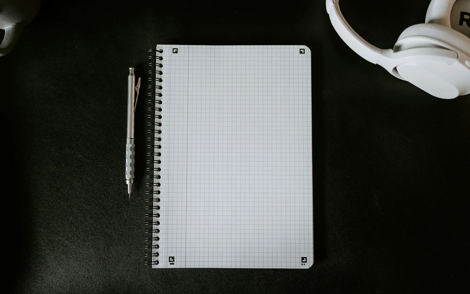 A notepad and pen beside a mug